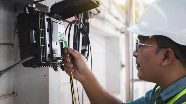 Engineer or technician checking fiber optic cables in internet splitter box